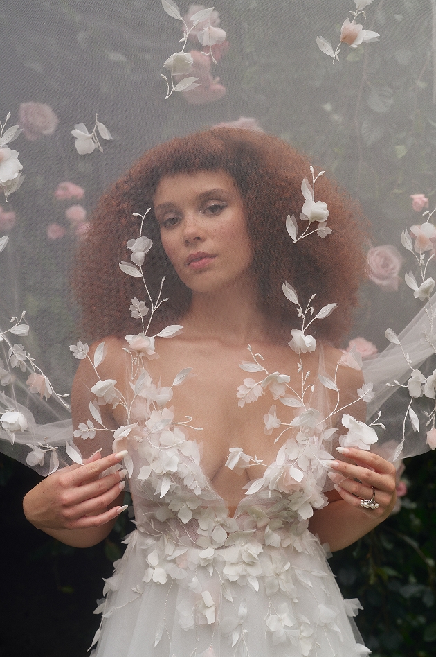 model in dress with floral petal applique top, low lounge, standing behind veil