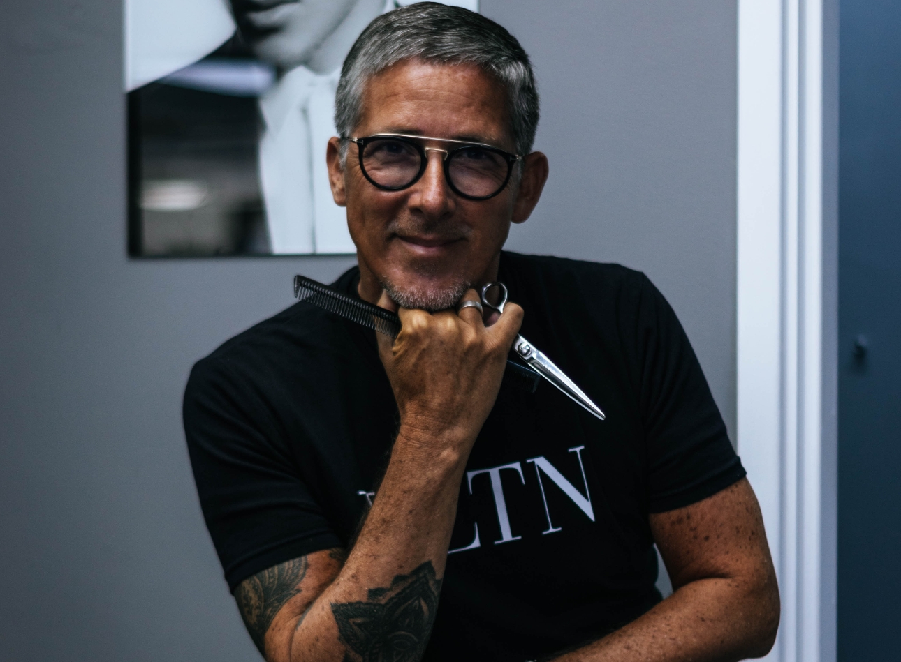 man sitting backwards in a chair holding hairdressing scissors