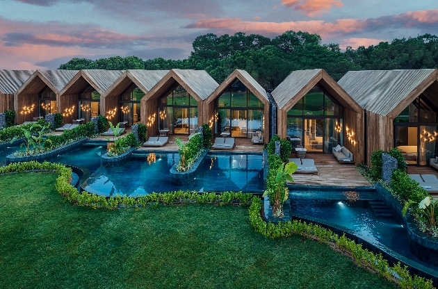 Several villas with pools surrounded by grass